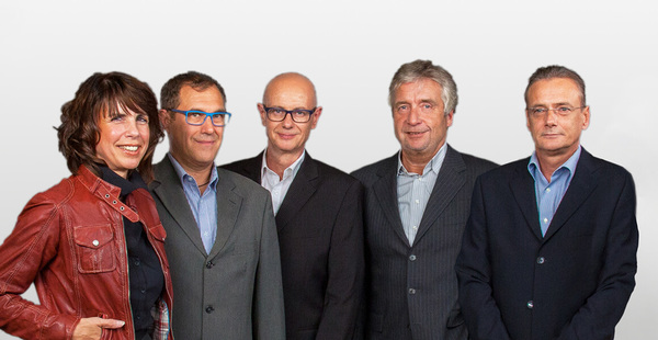 Fünf Geschäftsleute in Businesskleidung stehen gemeinsam vor hellem Hintergrund.